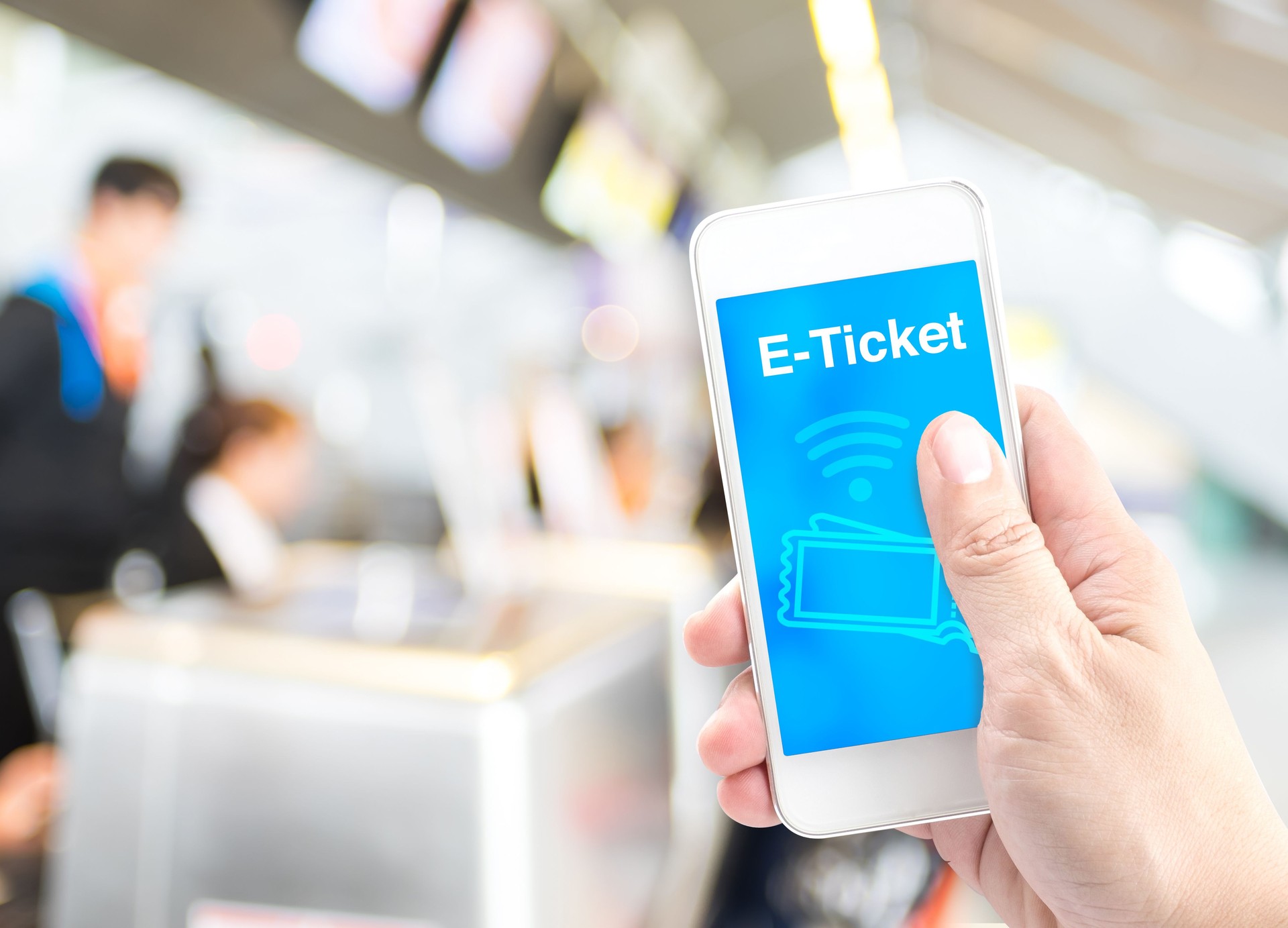 Hand holding mobile with E-Ticket with blur airport check-in bac