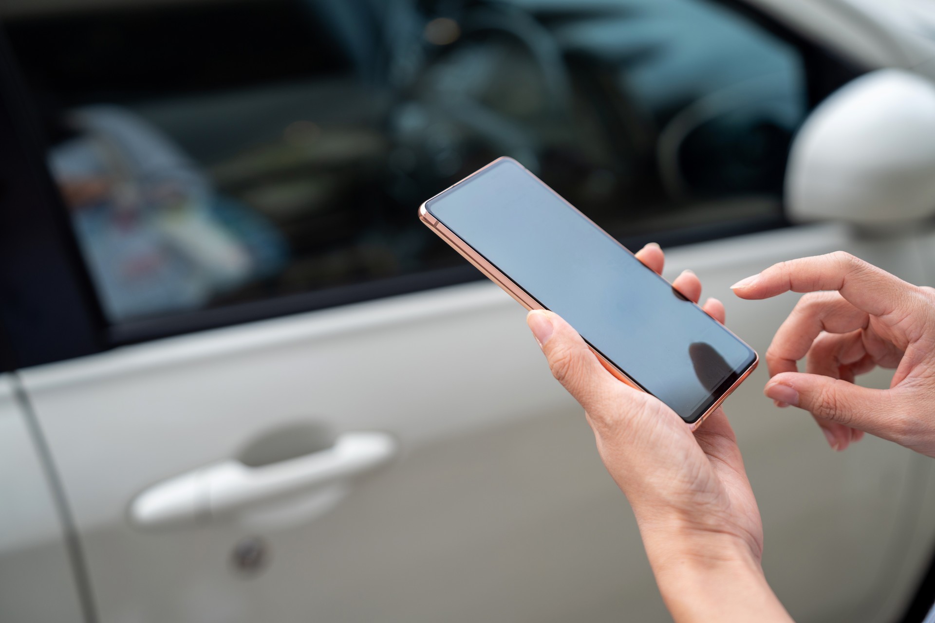 Close up person using mobile app device on smartphone to unlock car doors